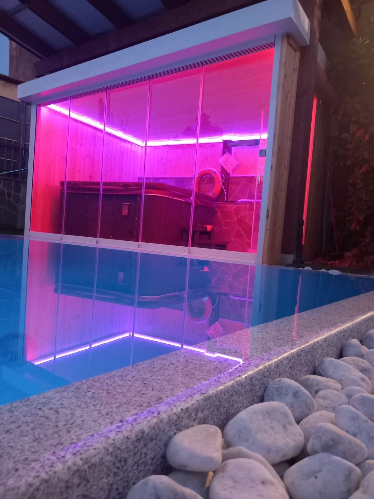Spa illuminata in rosa con riflesso in piscina